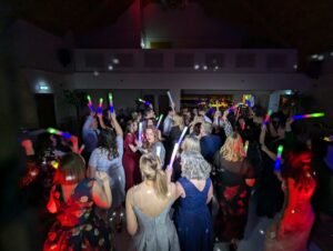 Wedding guests dancing with glow sticks on a packed dance floor at Heritage Park Hotel Porth, South Wales