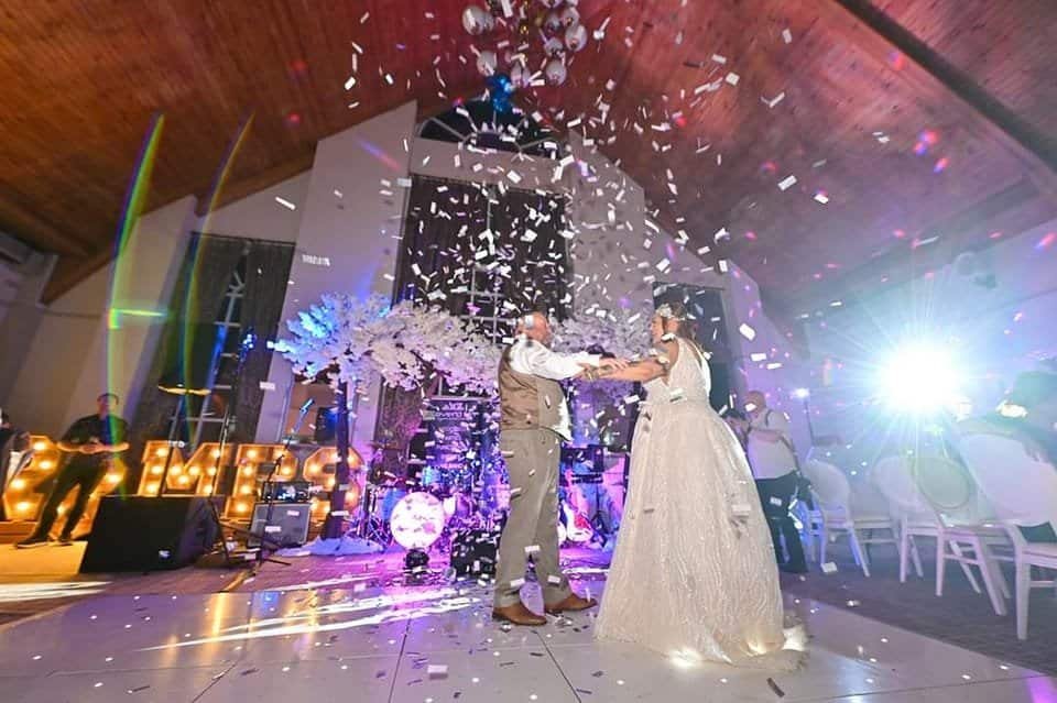Wedding couple dancing with confetti at glamorous reception event.