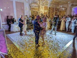 Elegant couple dancing at wedding reception with golden confetti.