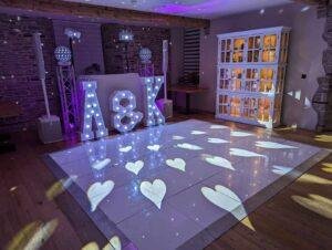 Wedding dance floor with illuminated initials "A & K" and heart-shaped light projections for a glamo.