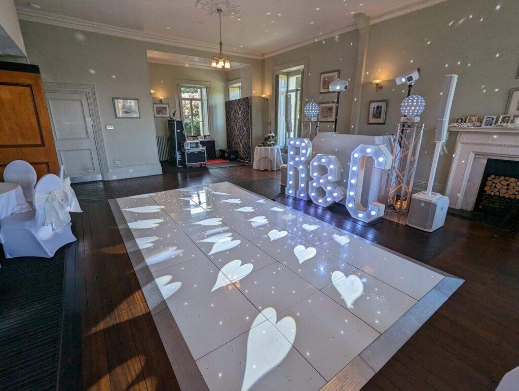 Wedding dance floor with illuminated hearts and starry light projections for a glamorous celebration.