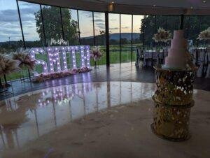Elegant wedding reception with illuminated "Mr & Mrs" sign and floral arrangements.